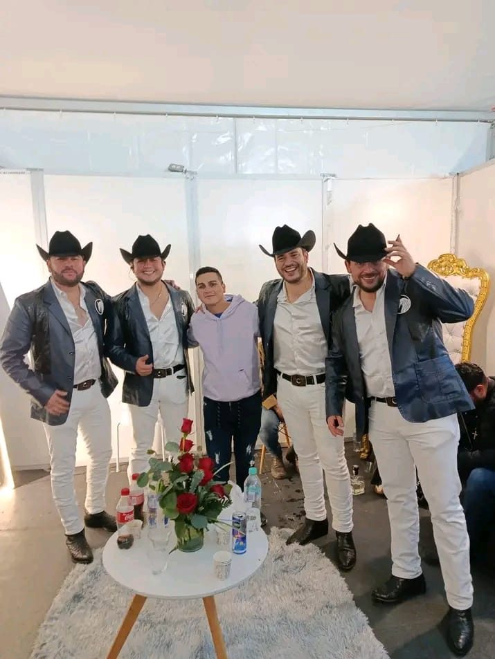 Cinco músicos con sombreros vaqueros posando frente a la cámara en un camerino