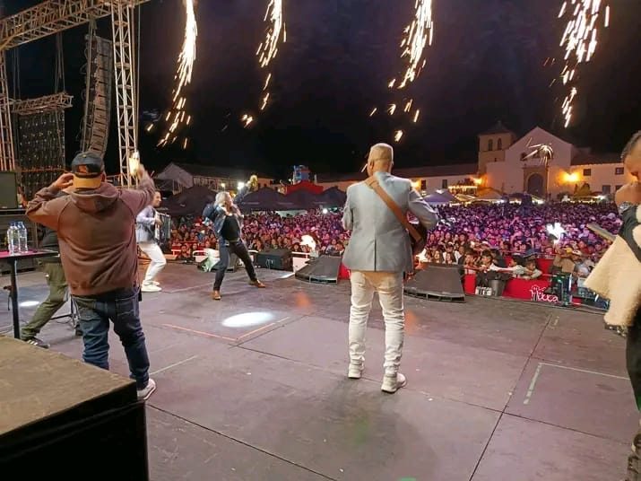 Tarima masiva al aire libre con pirotecnia, pantallas y una gran multitud durante un show en vivo